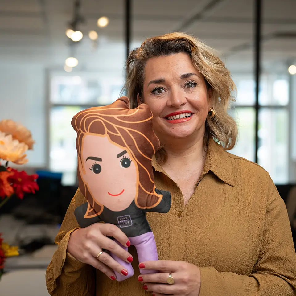 Liesbeth samen met haar knuffelportretje die op haar lijkt.